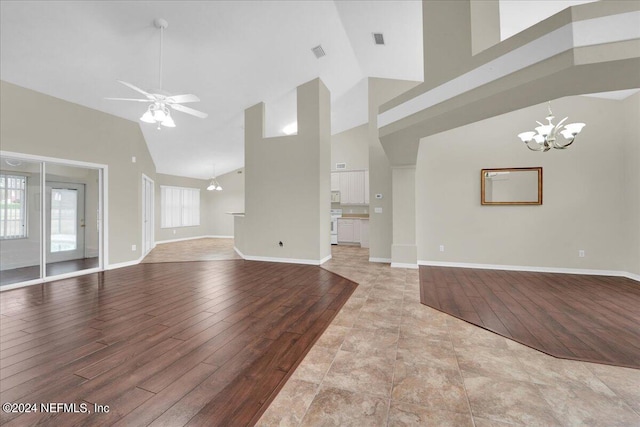 unfurnished living room with light tile floors, high vaulted ceiling, and ceiling fan with notable chandelier