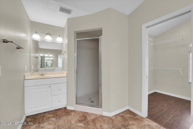 bathroom featuring tile floors, a shower with shower door, vanity with extensive cabinet space, and vaulted ceiling