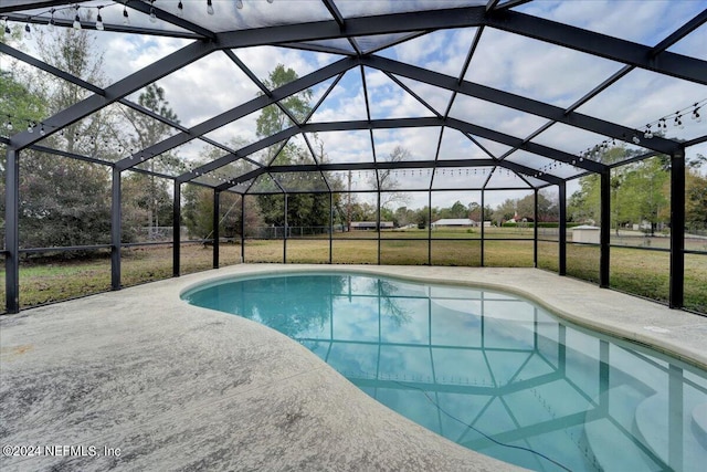 view of pool featuring a lawn, a patio area, and a lanai