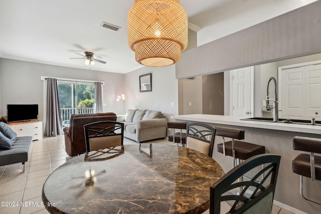 dining space with ceiling fan, light tile patterned floors, ornamental molding, and sink