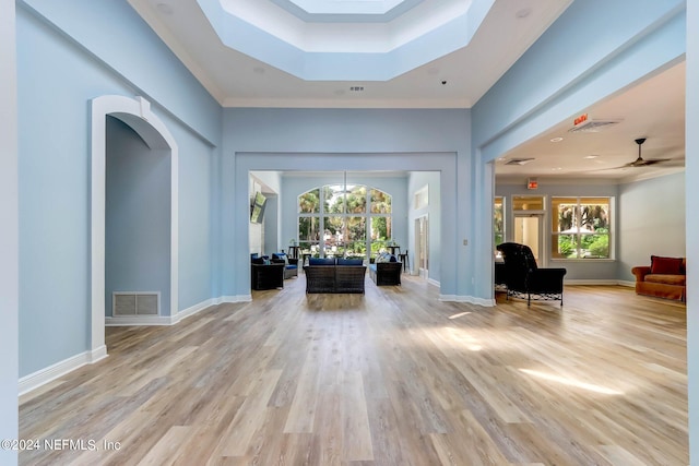 foyer entrance with a tray ceiling, light hardwood / wood-style floors, ornamental molding, and ceiling fan