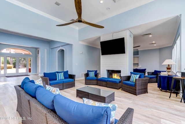 living room featuring ceiling fan, crown molding, light hardwood / wood-style floors, and a large fireplace