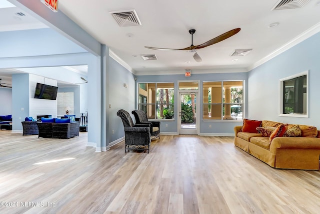 living room featuring ornamental molding, light wood-type flooring, and ceiling fan