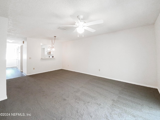 spare room with a textured ceiling, dark carpet, and ceiling fan with notable chandelier