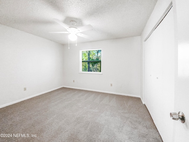 carpeted spare room featuring a textured ceiling and ceiling fan