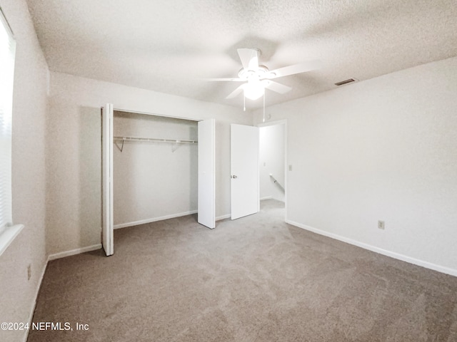 unfurnished bedroom with light colored carpet, a closet, ceiling fan, and a textured ceiling