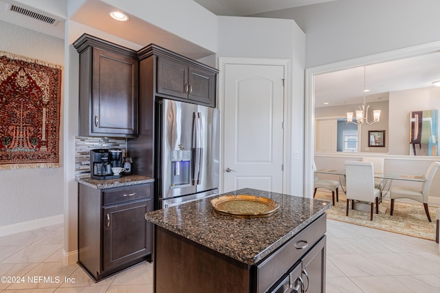 kitchen with dark stone counters, a center island, light tile patterned floors, stainless steel refrigerator with ice dispenser, and dark brown cabinets