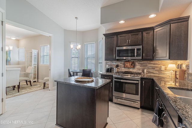 kitchen with a chandelier, a center island, light tile patterned floors, appliances with stainless steel finishes, and decorative backsplash