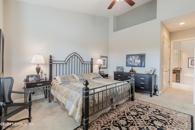 bedroom featuring ceiling fan, ensuite bathroom, and light colored carpet