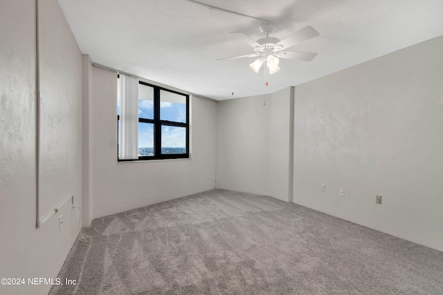 carpeted spare room featuring a textured ceiling and ceiling fan