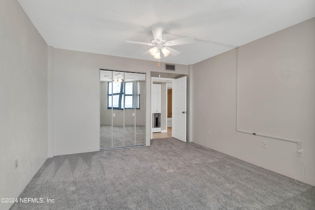 unfurnished room with a textured ceiling, ceiling fan, and carpet