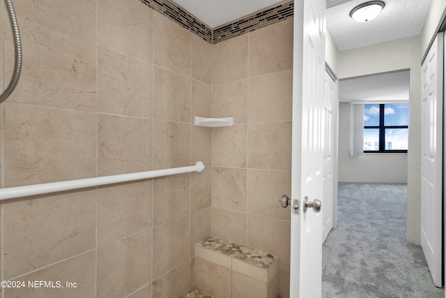 bathroom featuring a textured ceiling and a tile shower