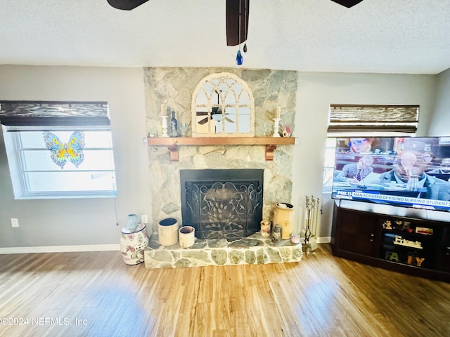 living room with ceiling fan, a fireplace, a textured ceiling, and hardwood / wood-style floors