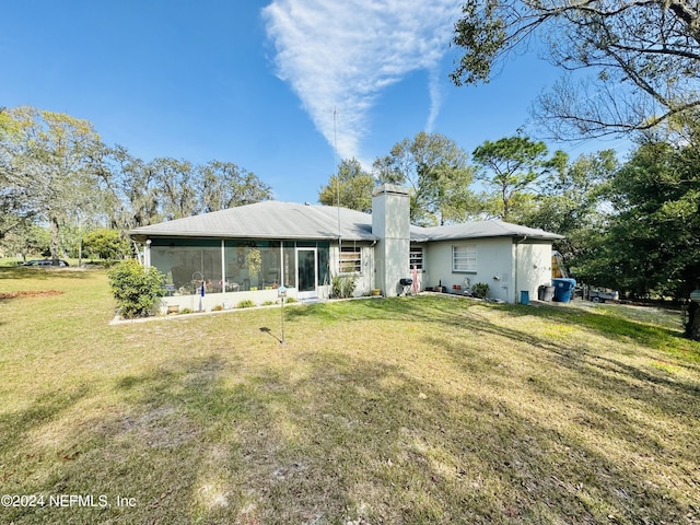 rear view of property with a sunroom and a yard