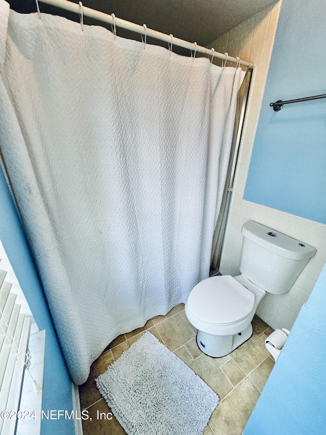 bathroom with tile patterned floors, a shower with curtain, and toilet