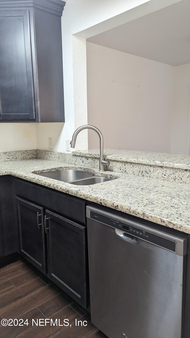 kitchen featuring light stone counters, stainless steel dishwasher, dark wood-type flooring, and sink