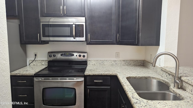 kitchen with light stone countertops, appliances with stainless steel finishes, and sink