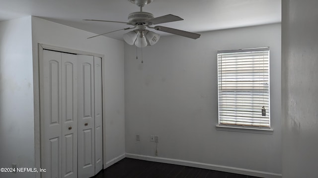 unfurnished bedroom with dark hardwood / wood-style flooring, a closet, and ceiling fan