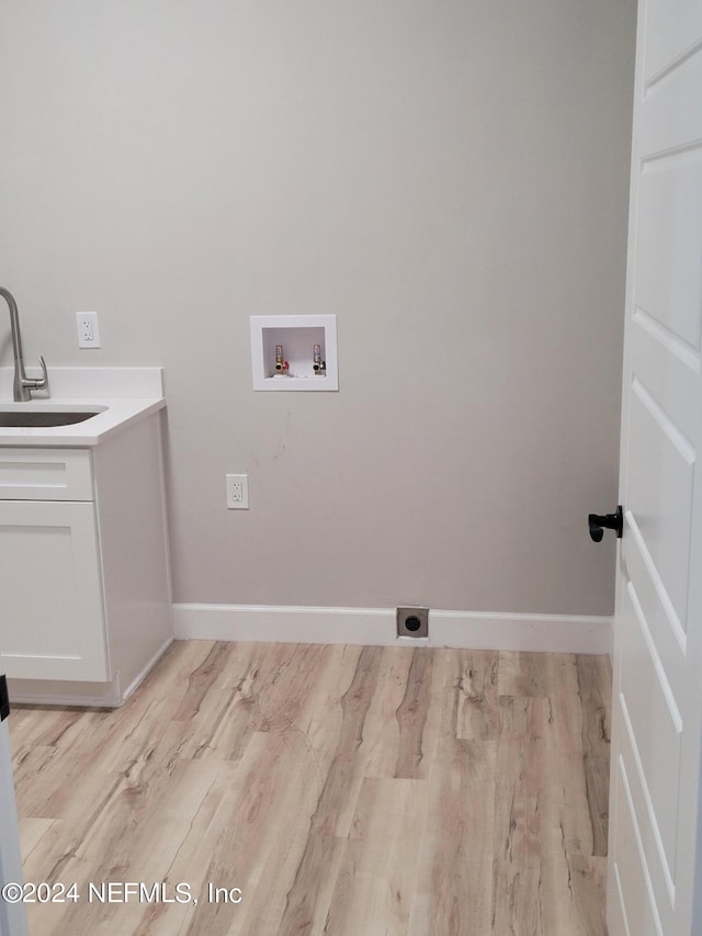 clothes washing area featuring washer hookup, hookup for an electric dryer, sink, light hardwood / wood-style floors, and cabinets