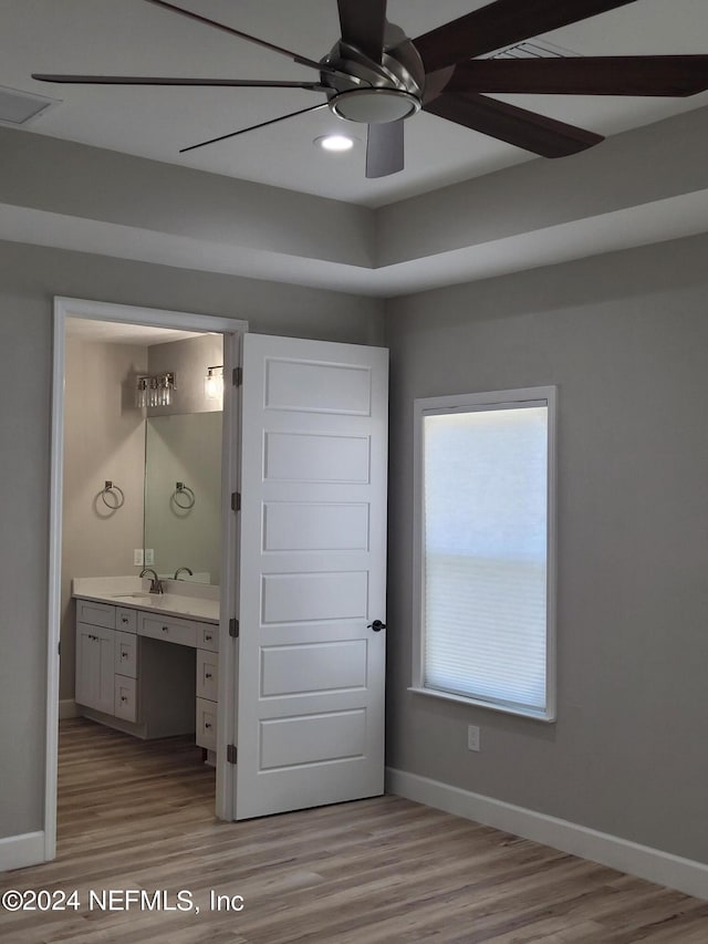 unfurnished bedroom with ensuite bath, ceiling fan, sink, and light hardwood / wood-style flooring