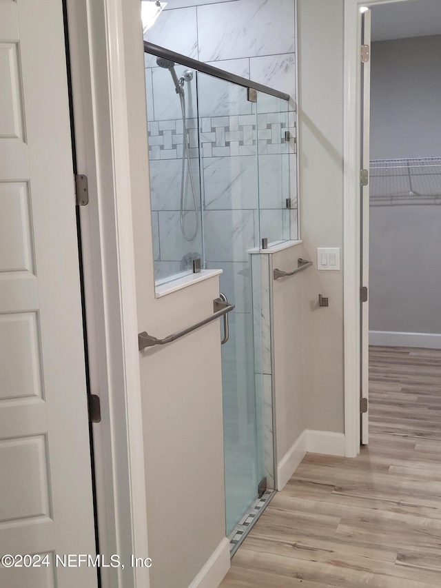 bathroom featuring a shower with door and wood-type flooring