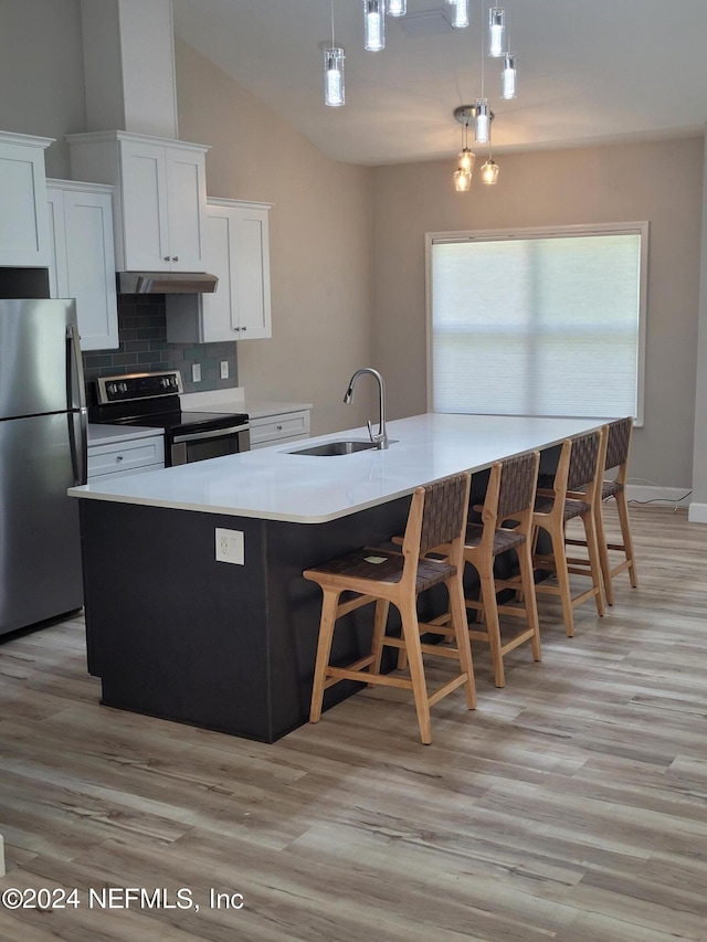 kitchen with sink, stainless steel appliances, vaulted ceiling, tasteful backsplash, and pendant lighting