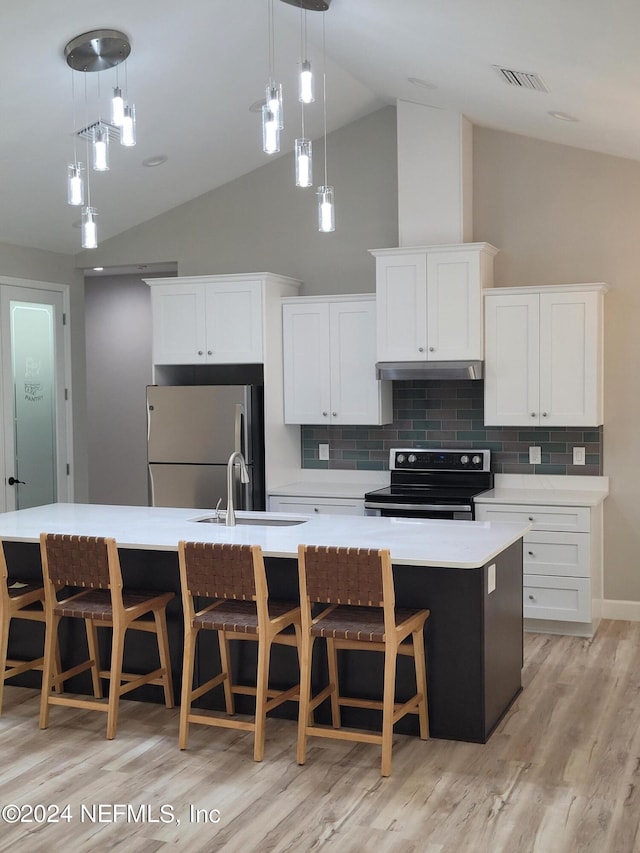 kitchen featuring light hardwood / wood-style floors, range with electric stovetop, a center island with sink, stainless steel refrigerator, and pendant lighting