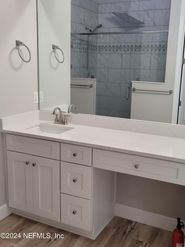 bathroom with vanity, tiled shower, and wood-type flooring