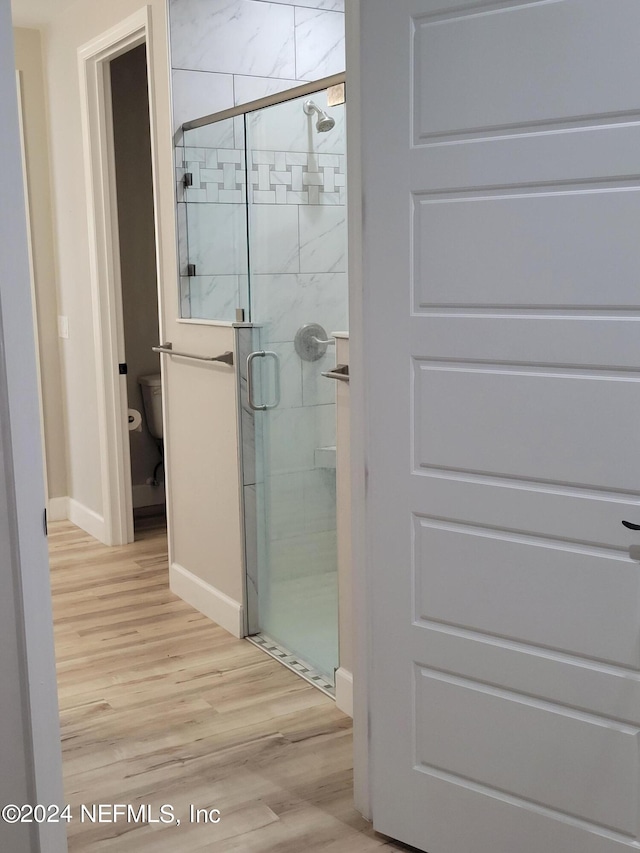 bathroom featuring toilet, an enclosed shower, and hardwood / wood-style flooring