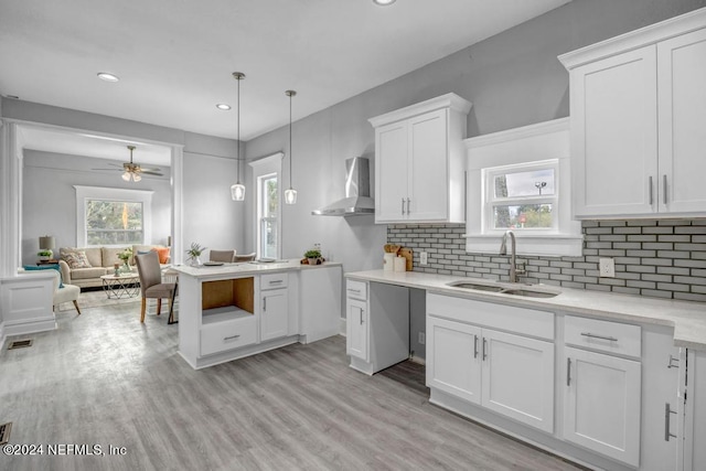 kitchen with ceiling fan, pendant lighting, sink, light hardwood / wood-style floors, and wall chimney range hood