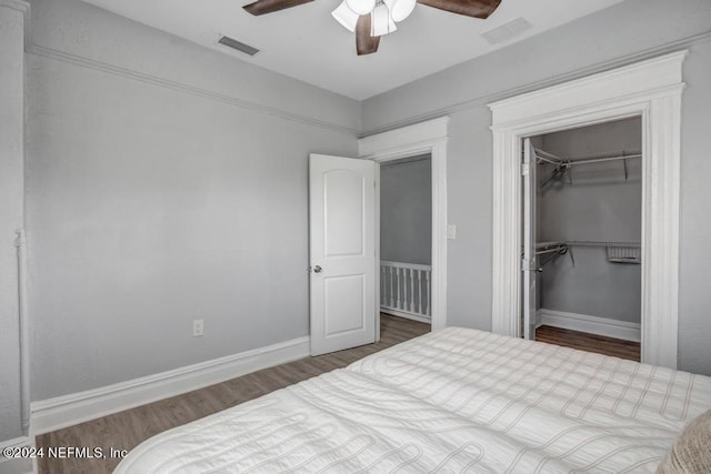 bedroom with a spacious closet, a closet, ceiling fan, and dark hardwood / wood-style flooring