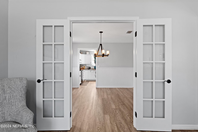 hall with a chandelier and light wood-type flooring