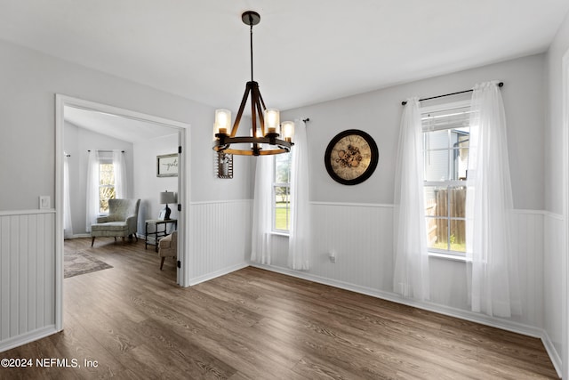 unfurnished dining area with lofted ceiling, a chandelier, a healthy amount of sunlight, and light wood-type flooring