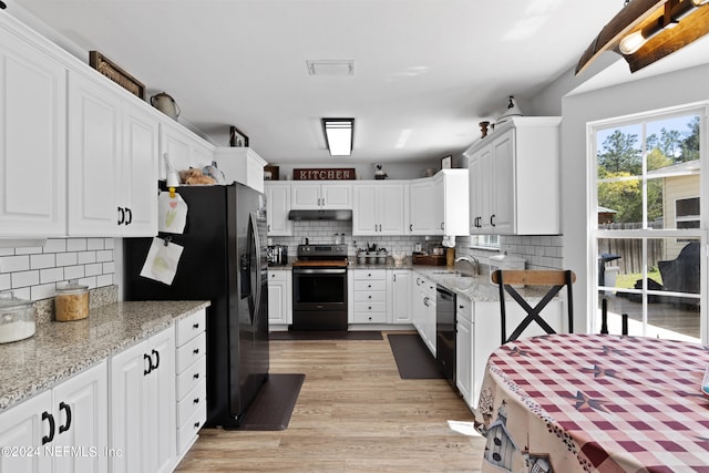 kitchen with light stone countertops, tasteful backsplash, black appliances, white cabinets, and light wood-type flooring