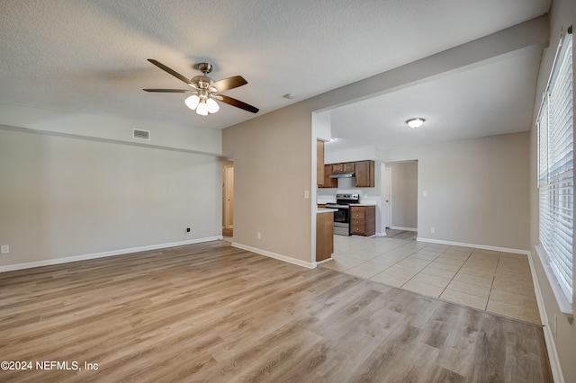 unfurnished living room with a textured ceiling, ceiling fan, and light tile floors