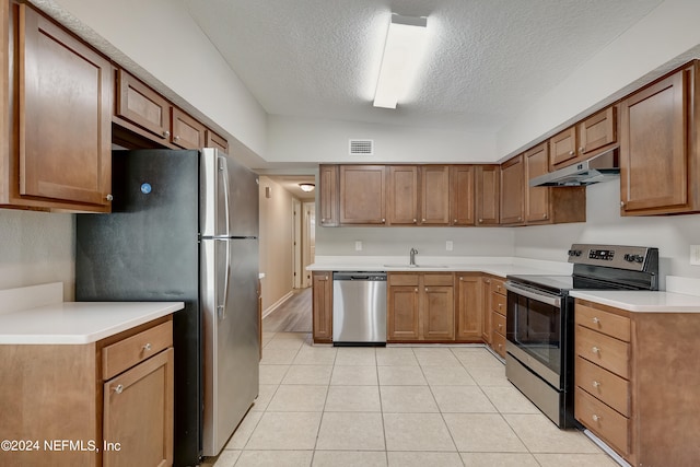 kitchen with lofted ceiling, appliances with stainless steel finishes, sink, light wood-type flooring, and a textured ceiling