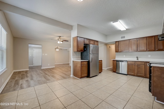 kitchen with ceiling fan, light tile flooring, sink, stainless steel appliances, and a textured ceiling