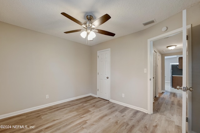 unfurnished bedroom featuring a textured ceiling, ceiling fan, and light hardwood / wood-style flooring