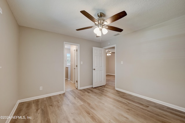 spare room with light hardwood / wood-style floors, a textured ceiling, and ceiling fan