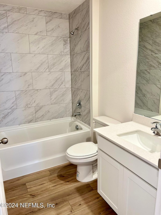 full bathroom with toilet, vanity, wood-type flooring, and tiled shower / bath