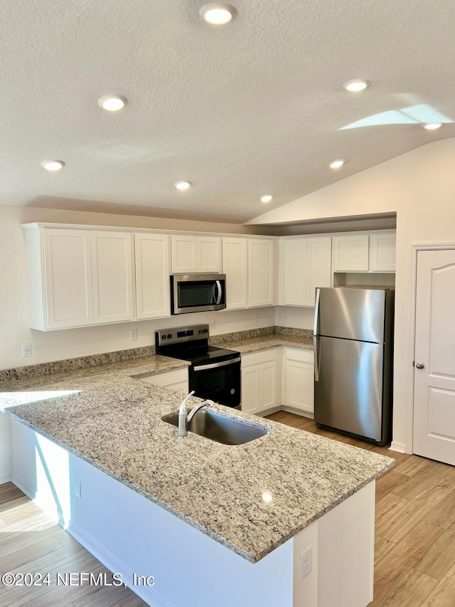 kitchen featuring lofted ceiling, light hardwood / wood-style flooring, appliances with stainless steel finishes, light stone counters, and white cabinetry