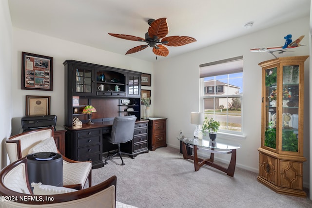 office space featuring a ceiling fan, light colored carpet, and baseboards