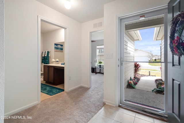 entrance foyer with light colored carpet, visible vents, baseboards, and light tile patterned floors