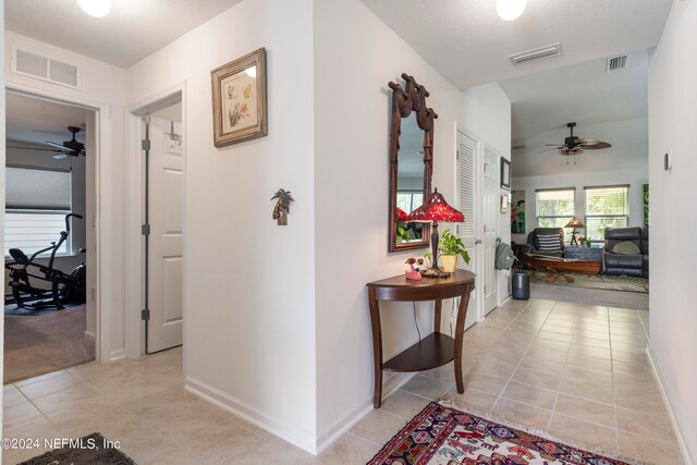 corridor with baseboards, visible vents, and light tile patterned flooring