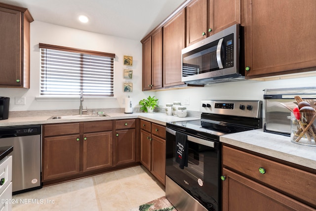 kitchen with light tile patterned floors, stainless steel appliances, a sink, and light countertops