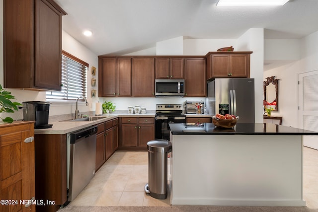 kitchen with lofted ceiling, light tile patterned floors, a kitchen island, a sink, and appliances with stainless steel finishes