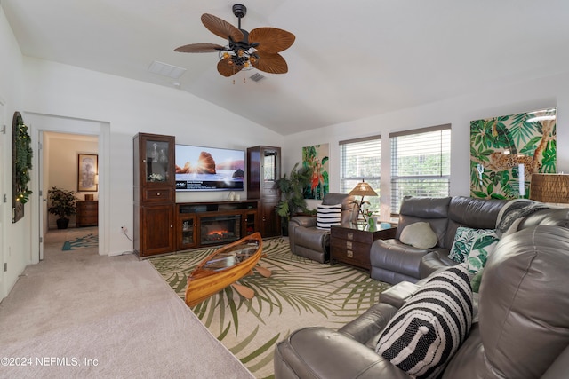 living room with visible vents, a glass covered fireplace, lofted ceiling, light colored carpet, and ceiling fan