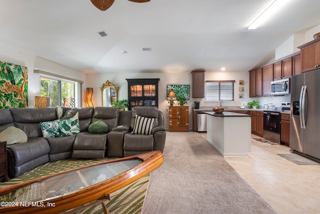 living room featuring lofted ceiling, light tile patterned floors, visible vents, and a healthy amount of sunlight