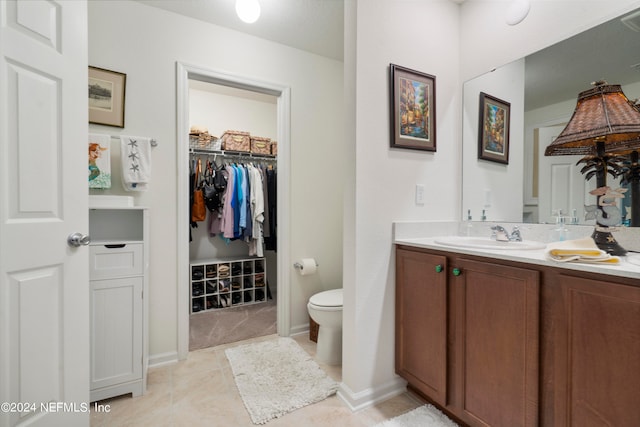 bathroom with toilet, tile patterned floors, baseboards, and vanity