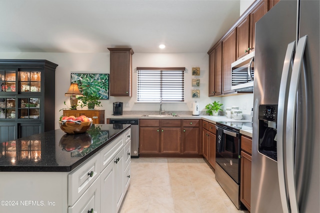 kitchen featuring a kitchen island, appliances with stainless steel finishes, dark stone countertops, a sink, and light tile patterned flooring